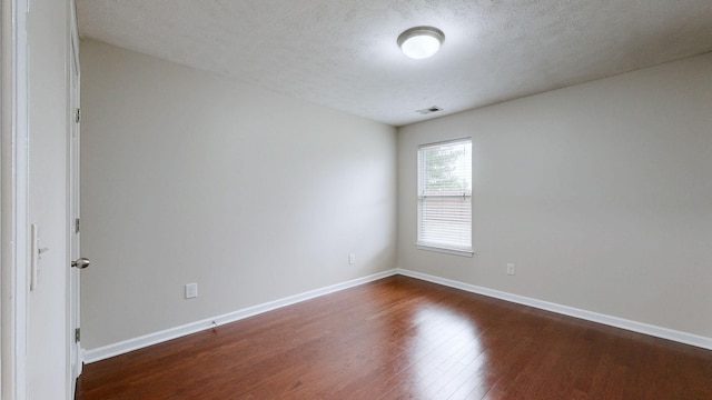 spare room with dark hardwood / wood-style flooring and a textured ceiling