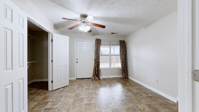 unfurnished bedroom with ceiling fan and a textured ceiling