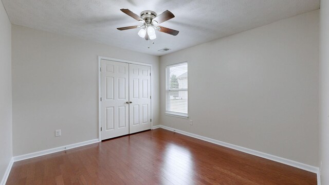 unfurnished bedroom with dark hardwood / wood-style floors, ceiling fan, and a closet