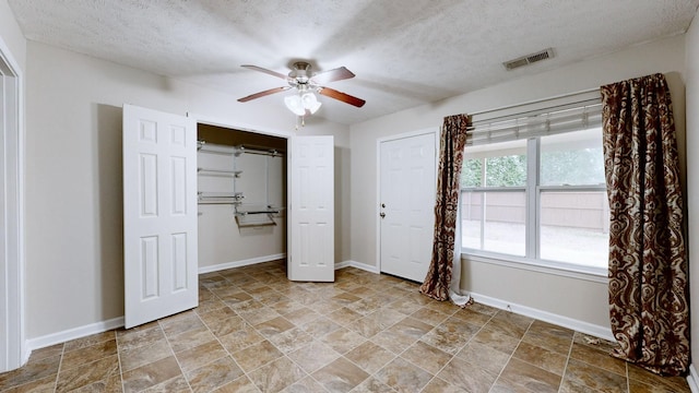 unfurnished bedroom with ceiling fan and a textured ceiling