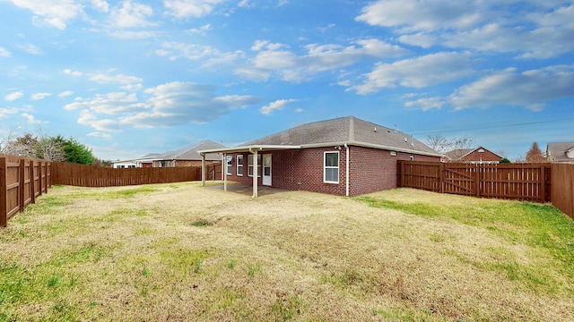 rear view of house featuring a lawn and a patio