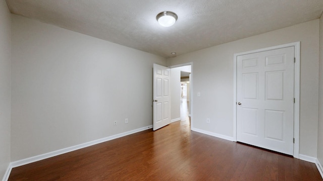 unfurnished bedroom with dark wood-type flooring and a textured ceiling