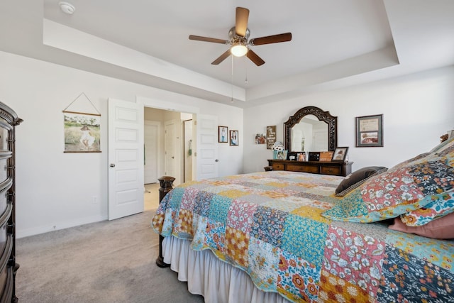 bedroom featuring ceiling fan, a raised ceiling, and light carpet