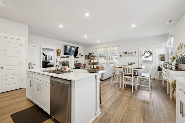 kitchen featuring sink, light wood-type flooring, stainless steel dishwasher, an island with sink, and white cabinets