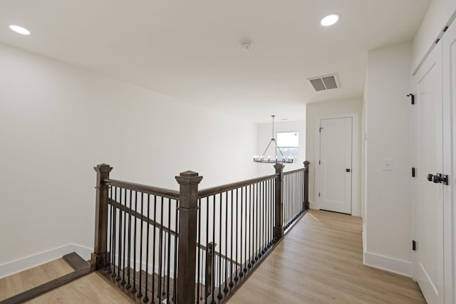 hallway with a chandelier and light wood-type flooring