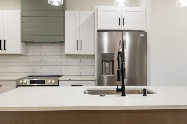 kitchen featuring stainless steel appliances, white cabinets, and backsplash