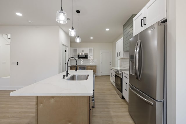 kitchen with pendant lighting, sink, a kitchen island with sink, stainless steel appliances, and white cabinets