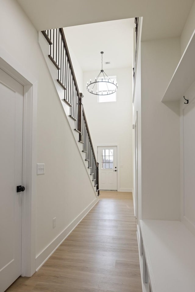 foyer with a towering ceiling, a chandelier, and light hardwood / wood-style floors