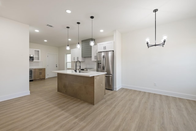 kitchen featuring sink, white cabinetry, decorative light fixtures, appliances with stainless steel finishes, and an island with sink