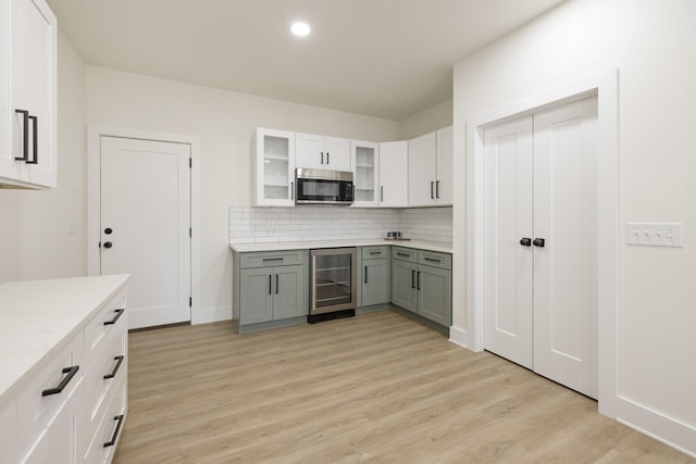 kitchen with white cabinetry, beverage cooler, light hardwood / wood-style floors, and tasteful backsplash