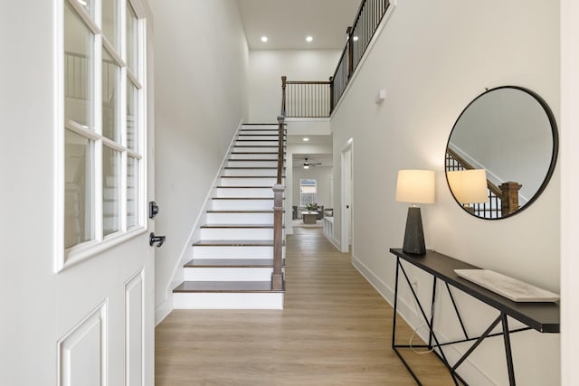 interior space with a towering ceiling, light hardwood / wood-style flooring, and ceiling fan