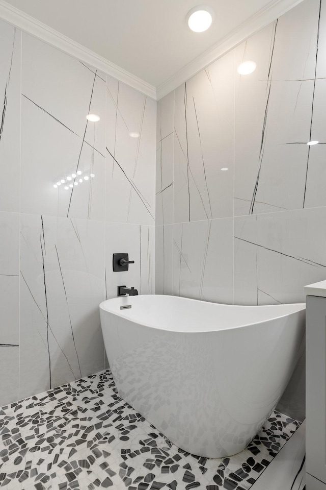 bathroom with tile walls, ornamental molding, and a tub