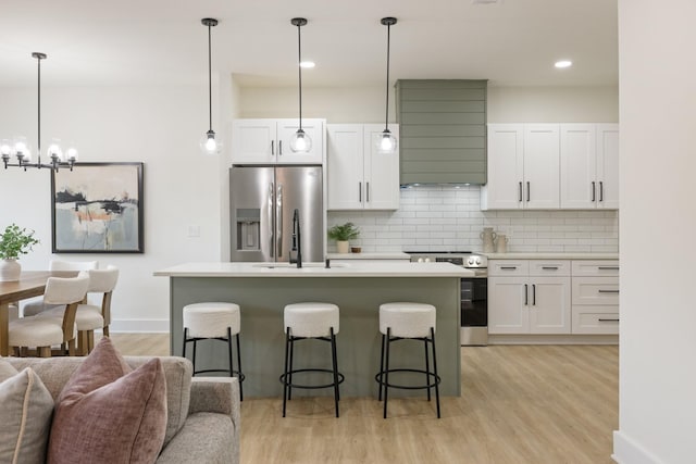 kitchen featuring decorative light fixtures, stainless steel appliances, and white cabinets