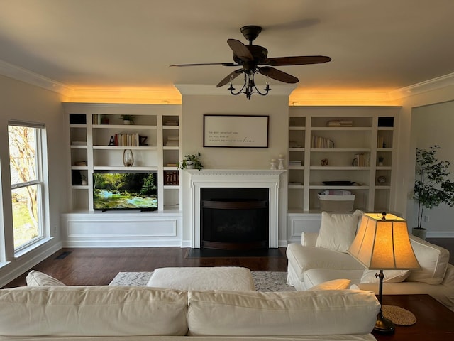 living room with crown molding, ceiling fan, dark hardwood / wood-style flooring, and built in shelves