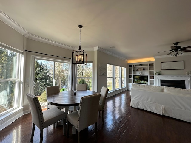 dining room featuring crown molding, dark wood-type flooring, a wealth of natural light, and built in shelves