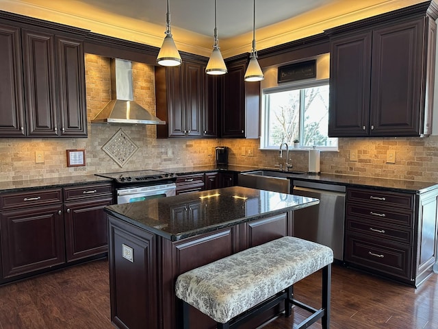 kitchen featuring sink, hanging light fixtures, a center island, stainless steel appliances, and wall chimney exhaust hood