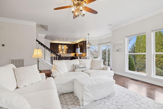 living room with crown molding, wood-type flooring, and ceiling fan with notable chandelier