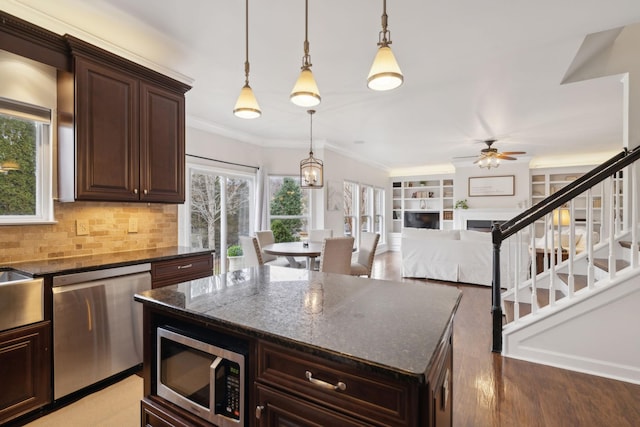 kitchen with a kitchen island, dark stone countertops, hanging light fixtures, stainless steel appliances, and dark brown cabinets