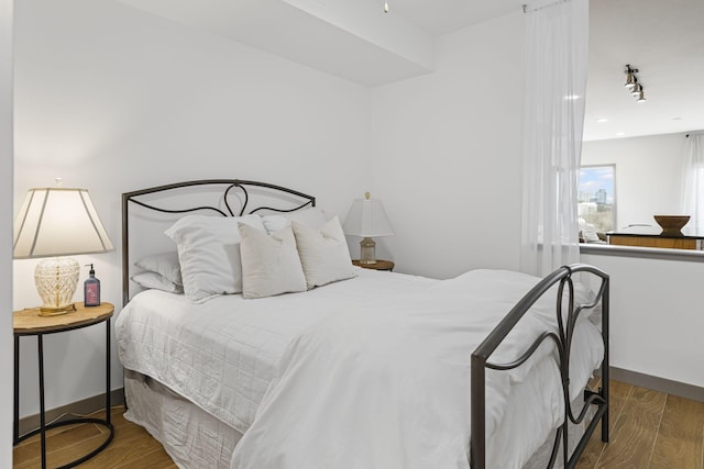 bedroom featuring track lighting and dark hardwood / wood-style flooring