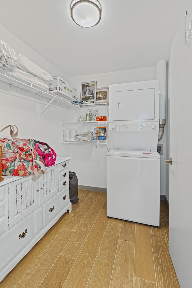 laundry room with stacked washing maching and dryer and light hardwood / wood-style floors