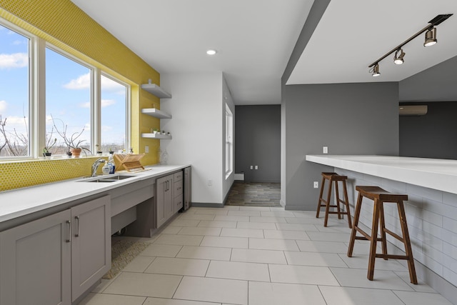 kitchen featuring sink, a breakfast bar area, a wall mounted AC, gray cabinets, and backsplash