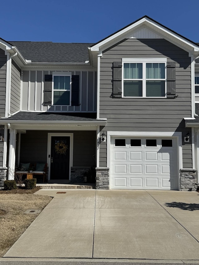 view of front facade featuring a garage, covered porch, stone siding, and concrete driveway