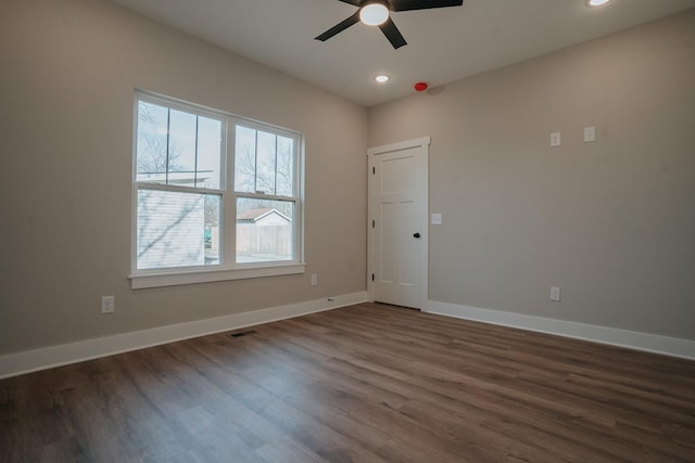 spare room with dark hardwood / wood-style flooring and ceiling fan