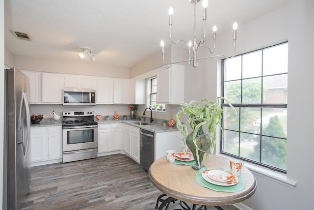 kitchen with sink, plenty of natural light, stainless steel appliances, light stone counters, and white cabinets