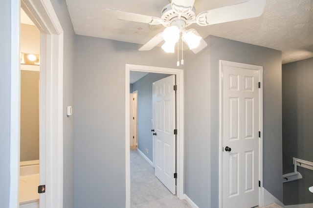 hall with light colored carpet and a textured ceiling