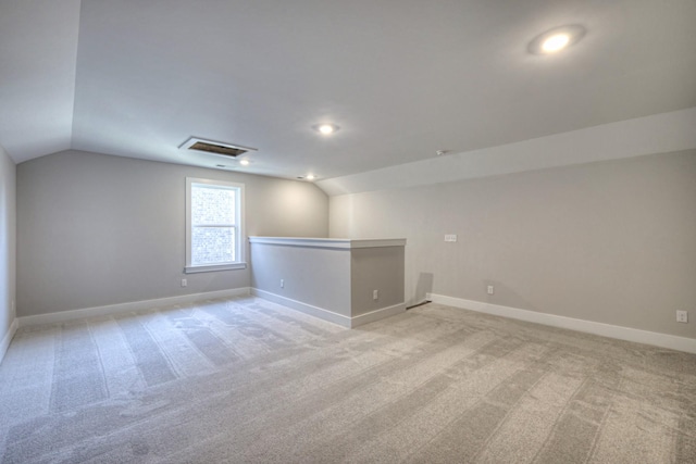 additional living space featuring vaulted ceiling and light carpet