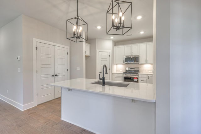 kitchen featuring pendant lighting, sink, white cabinetry, and appliances with stainless steel finishes