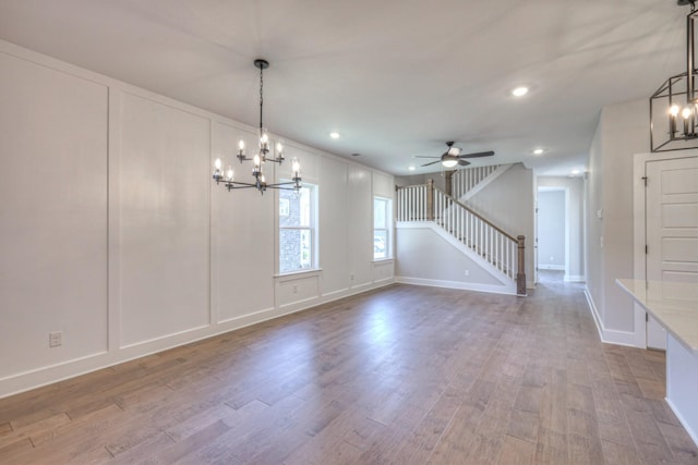 empty room with hardwood / wood-style flooring and ceiling fan with notable chandelier