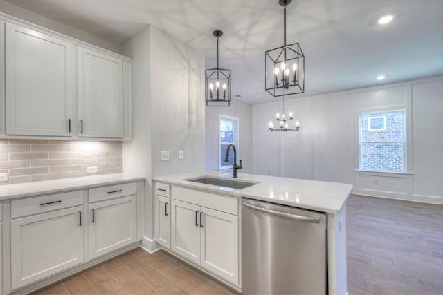 kitchen featuring white cabinetry, stainless steel dishwasher, sink, and hanging light fixtures