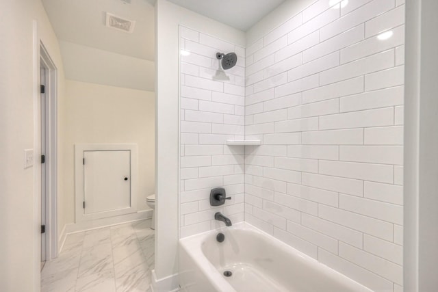 bathroom featuring tiled shower / bath combo and toilet