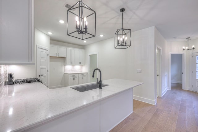 kitchen featuring hanging light fixtures, sink, white cabinets, and an inviting chandelier