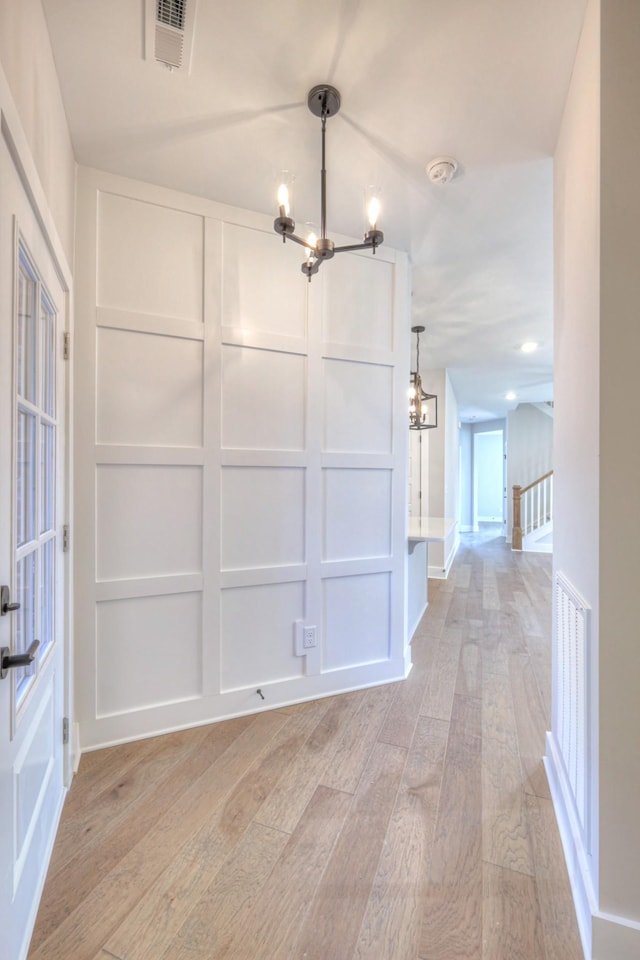 unfurnished dining area featuring vaulted ceiling, light wood-type flooring, and a chandelier