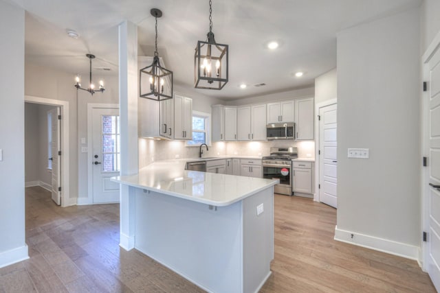 kitchen with stainless steel appliances, white cabinetry, pendant lighting, and kitchen peninsula