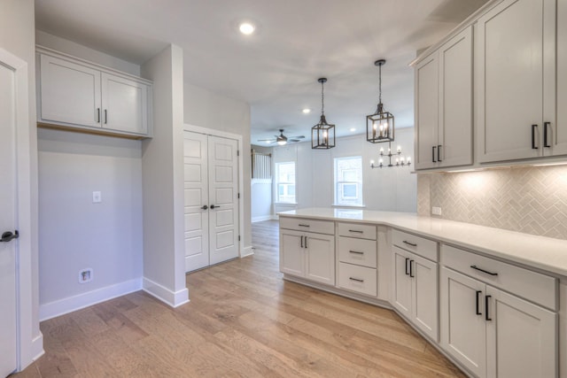 kitchen with white cabinetry, hanging light fixtures, decorative backsplash, kitchen peninsula, and light wood-type flooring