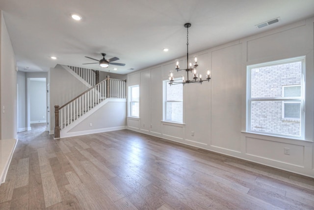 unfurnished room featuring ceiling fan with notable chandelier and light hardwood / wood-style flooring