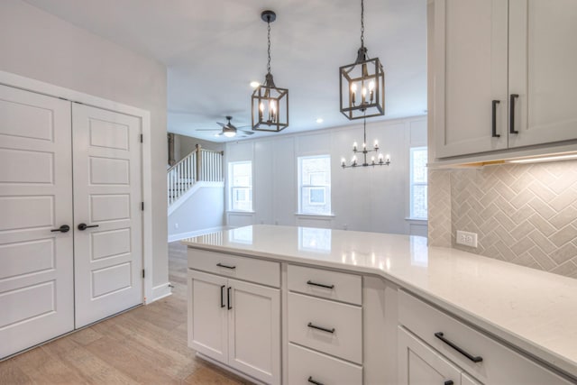 kitchen featuring backsplash, decorative light fixtures, light hardwood / wood-style flooring, and white cabinets