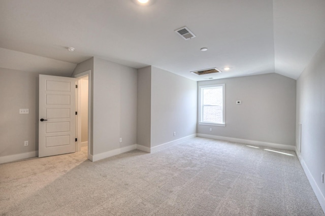 spare room featuring lofted ceiling and light carpet