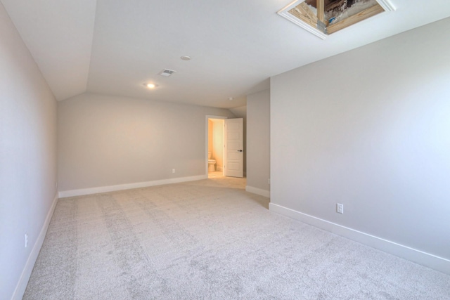 spare room featuring lofted ceiling and light colored carpet