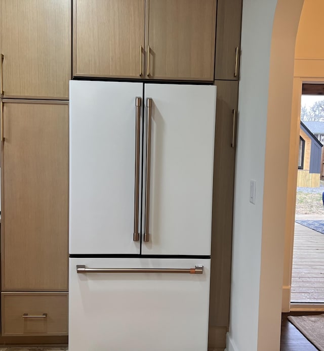 interior details featuring high end fridge, light brown cabinetry, and dark wood-type flooring