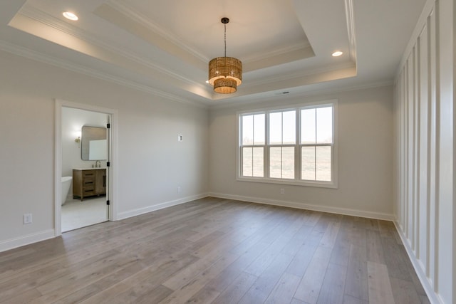 empty room featuring ornamental molding, a tray ceiling, and light hardwood / wood-style floors