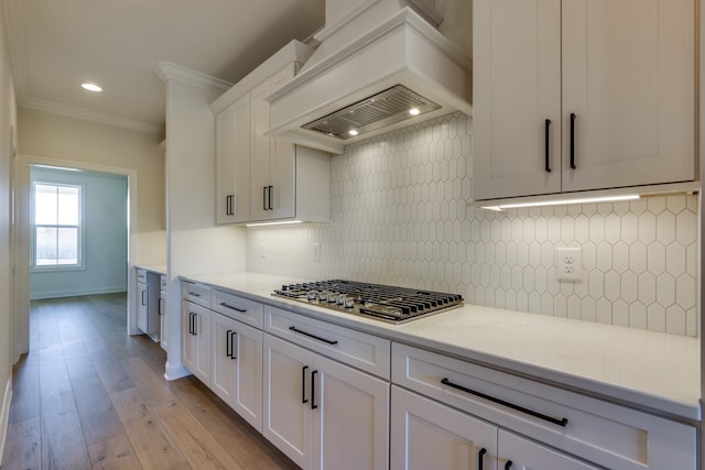 kitchen featuring white cabinetry, light stone countertops, custom range hood, and ornamental molding