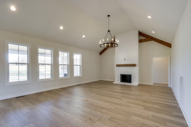 unfurnished living room with a chandelier, high vaulted ceiling, a brick fireplace, and light wood-type flooring