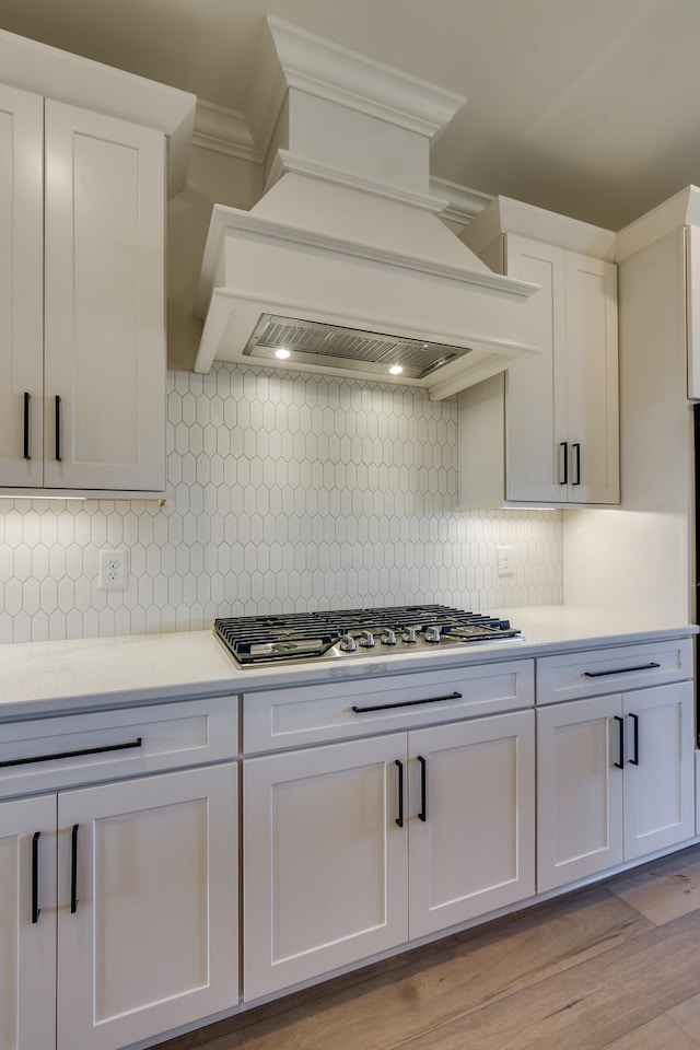 kitchen with white cabinetry, tasteful backsplash, stainless steel gas cooktop, and custom exhaust hood