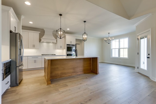 kitchen featuring stainless steel appliances, an island with sink, custom exhaust hood, and white cabinets