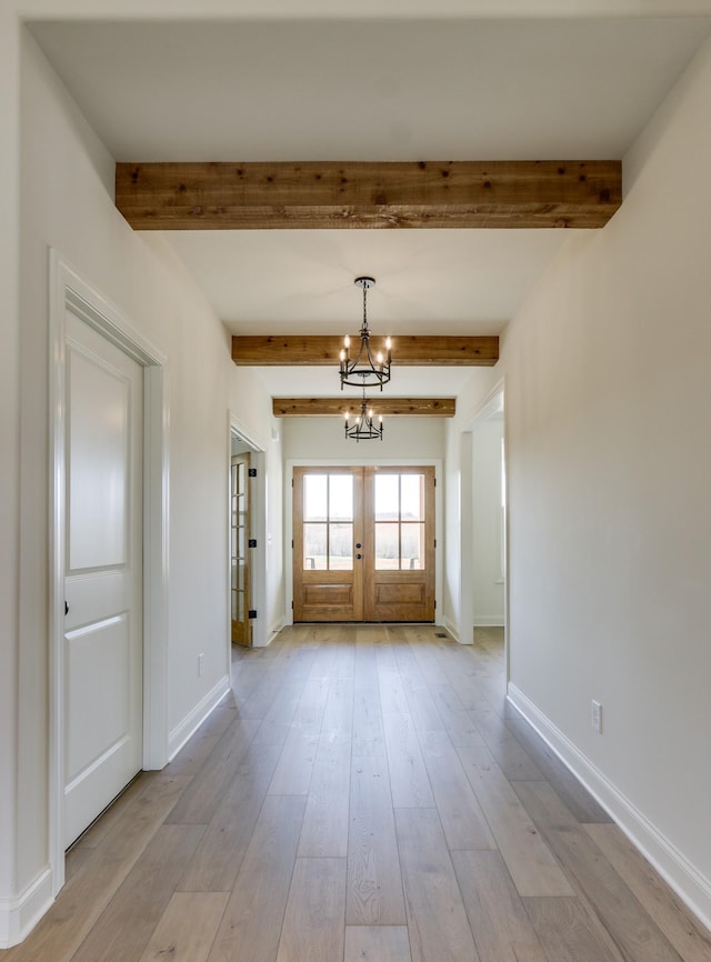 foyer entrance featuring a notable chandelier, beam ceiling, french doors, and light wood-type flooring