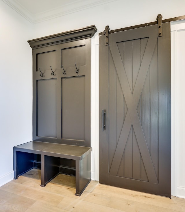 mudroom with crown molding, a barn door, and light hardwood / wood-style floors